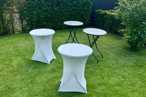 Statafels huren Partytent-Zwolle Vier grijze statafels, waarvan twee met witte tafelrok, staan in gras gefotografeerd van bovenaf in tuin.